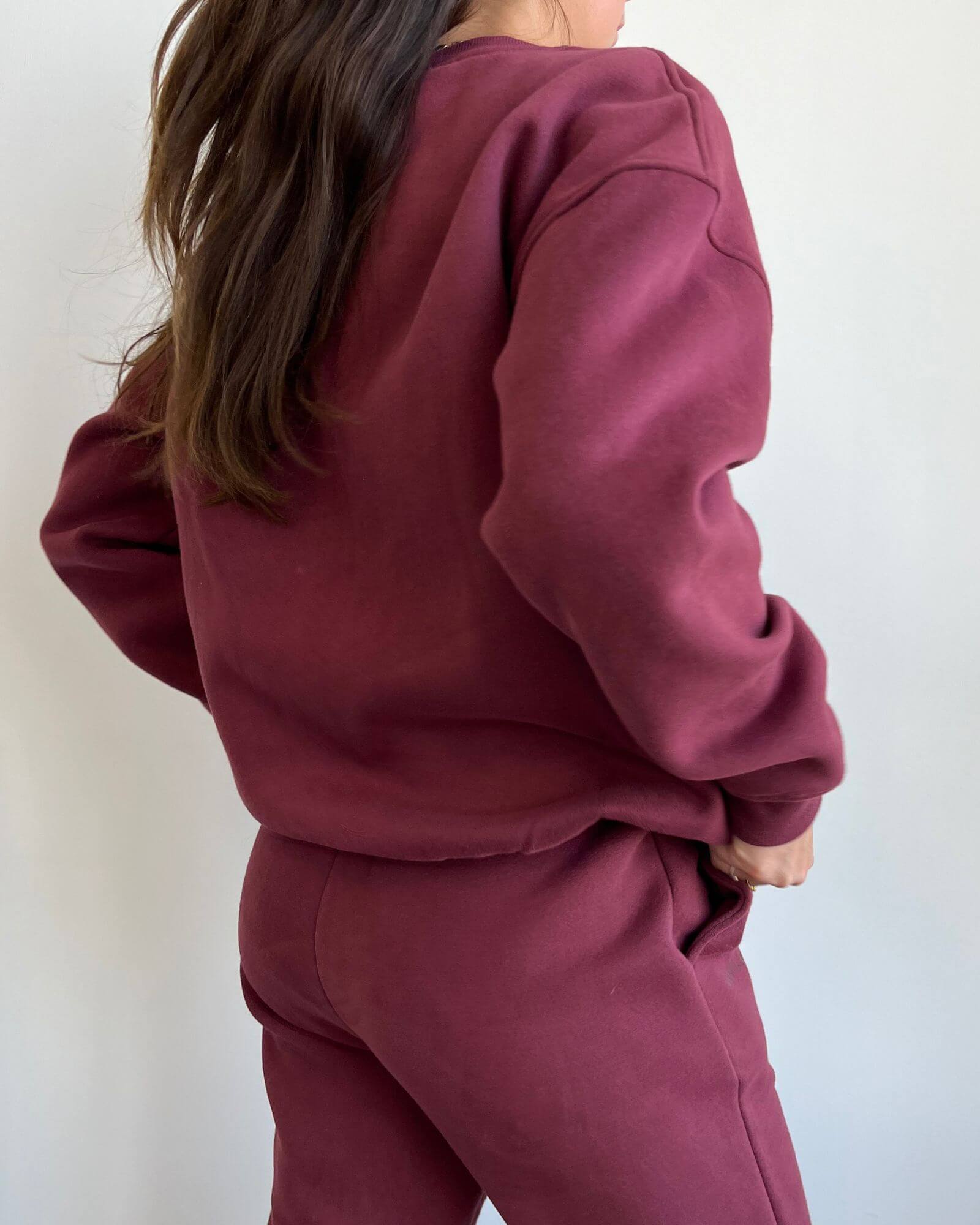 Back view of a girl wearing a cute burgundy matching set in front of a white background.