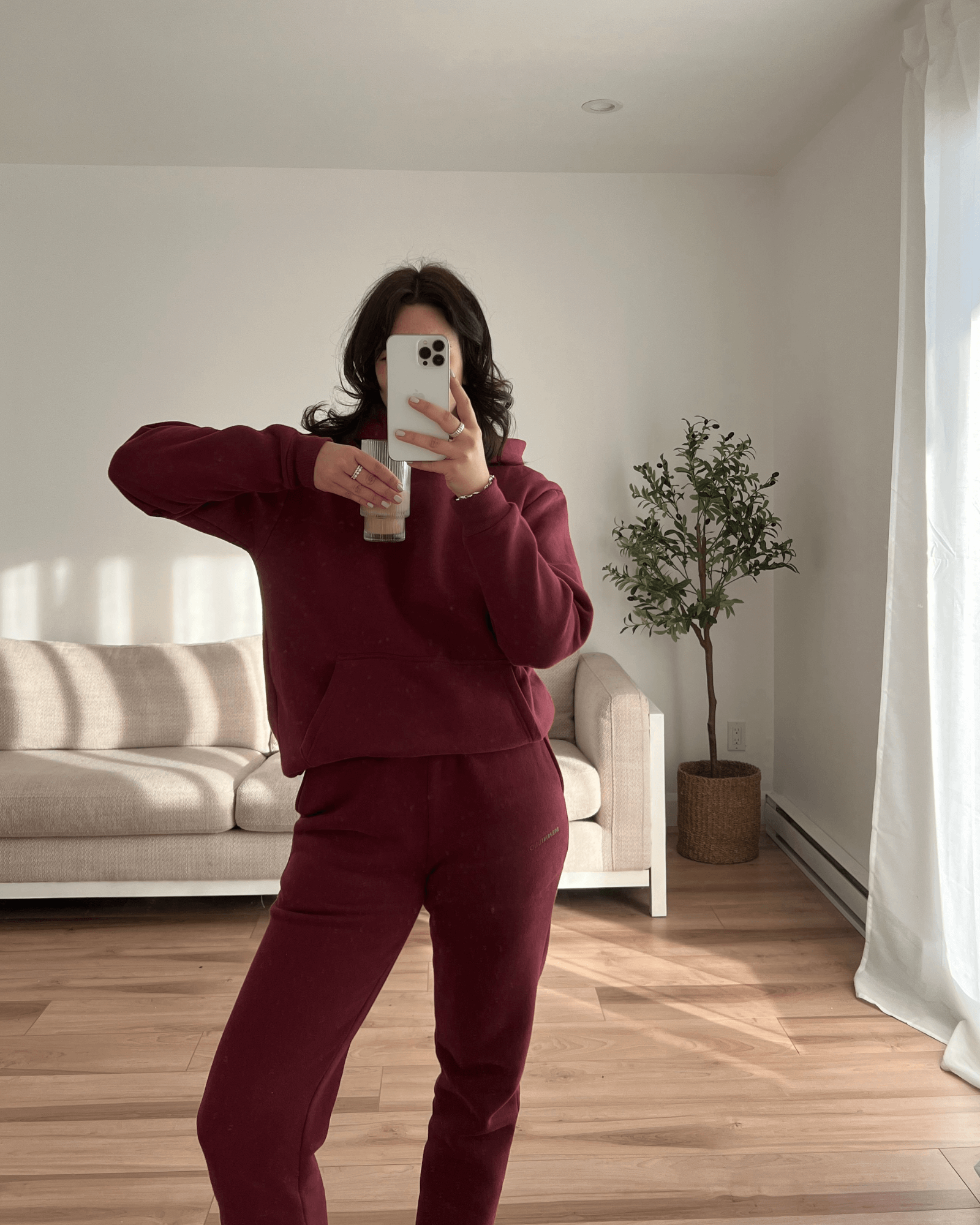 Mirror picture of a brunette girl wearing a cute matching set in her house while drinking her coffee.