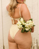 Back view of a pretty girl holding a bouquet of flowers in her cute floral yellow bikini.