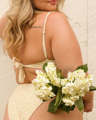 Back view of a pretty girl holding a bouquet of flowers in her cute floral yellow bikini.